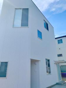 een wit gebouw met een deur aan de zijkant bij Villa Monica EAST in Nagoya