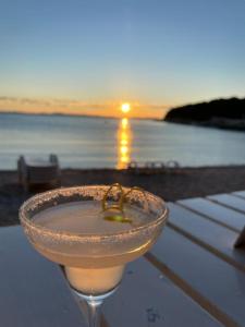 een wijnglas op een tafel met de zonsondergang op de achtergrond bij Mobilna kućica u Campu Rehut, plaža Slanica Murter in Murter