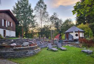 einen Garten mit Stühlen, einer Steinmauer und einem Gebäude in der Unterkunft Pension Kricklsäge in Philippsreut