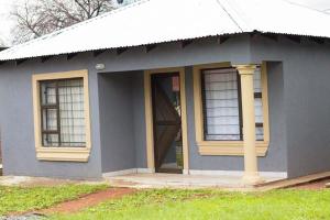 a blue house with two windows and a porch at Tranquility at Homely Escape in Phalaborwa