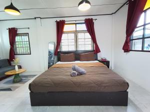 a bedroom with a large bed with red curtains at THE NAIYANGHOUSE in Nai Yang Beach