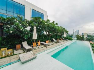 胡志明市的住宿－Serenity Saigon Sky Villas，一座大楼内的游泳池,配有椅子和遮阳伞