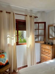 a bedroom with a bed and a window with curtains at Casa Los Palitos in Monte de Breña