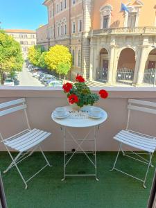 a table with two chairs and a vase of flowers on a balcony at Appartamento a uso turistico in Viterbo