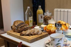 einen Tisch mit einem Schneidebrett mit Brot und Milchflaschen in der Unterkunft La Demeure de Camille 