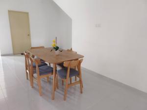 a wooden table and chairs with a vase of flowers on it at HOMESTAY MYROKMA in Kampong Belukar