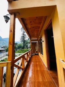 a balcony of a house with a wooden floor at ThePahadians Food & Stay in Jibhi