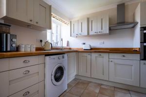 a kitchen with white cabinets and a washing machine at Cosy Northumbrian Cottage in Barrasford