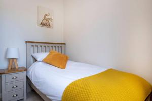 a bedroom with a bed with a yellow blanket and a nightstand at Cosy Northumbrian Cottage in Barrasford