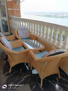 a balcony with wicker chairs and a table at شقة فندقيه فاخرة بمنطقة المعادى صف اول جميع الغرف تطل على النيل A luxury hotel apartment in Maadi, first row. All rooms overlook the Nile in Cairo