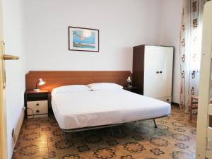 リド・ディ・イエゾロにあるVilla Postumiaの白いベッド1台(木製ヘッドボード付)が備わるベッドルーム1室が備わります。