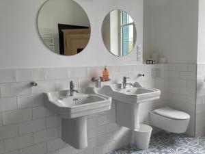 a bathroom with two sinks and a toilet and a mirror at Maison MOKASSI in Laloubère
