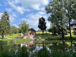 an old house next to a lake with trees at Domaine des Arches in Soumagne