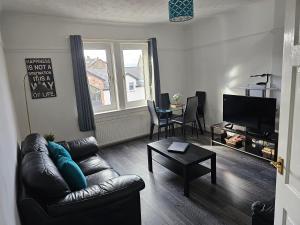 a living room with a leather couch and a table at Snug - Meadhan Apartment in Helensburgh