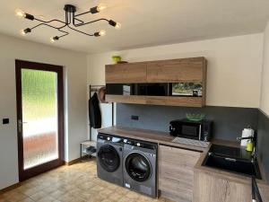 a kitchen with a washing machine and a microwave at Domaine des Arches in Soumagne