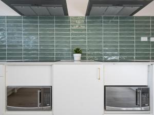 a green tiled wall in a kitchen with two microwaves at Lillou Hostels in Sydney