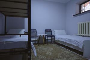 1 dormitorio con 2 camas, mesa y sillas en Almaty Backpackers, en Almaty