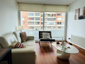 uma sala de estar com um sofá e uma mesa de vidro em Las Condes, Excelentes Apartamentos - Sofia Camilla Propiedades em Santiago