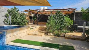 a backyard with a swimming pool and a wooden pergola at merana charlet in Ash Shāghūr
