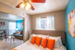 een slaapkamer met een bed met oranje kussens en een plafondventilator bij Entire Place King Bed Washer Dryer Fast WiFi 2 Cars #509 in Fort Worth