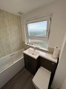 a bathroom with a sink and a tub and a window at The Wee Hoose Rhu in Rhu