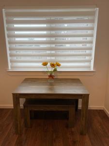 a table in front of a window with a vase with flowers at The Wee Hoose Rhu in Rhu