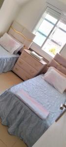 - une petite chambre avec 2 lits et une fenêtre dans l'établissement maison Halima, à Ifrane