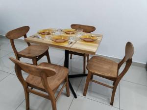 シティアワンにあるNana's Sitiawan Home Stay, Victoria cottageの木製テーブルと椅子(皿、ワイングラス付)