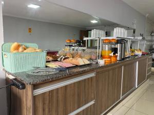 a kitchen with a counter top with bread andspectacular food at Nasser Hotel Aeroporto in Núcleo Bandeirante