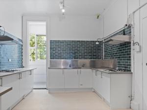 una cocina con armarios blancos y fregadero en VENUS Potts Point - FEMALE ONLY HOSTEL - Long stay negotiable en Sídney