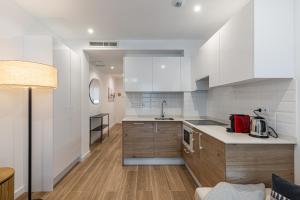 eine Küche mit weißen Wänden und Holzschränken in der Unterkunft BNBHolder Best III Madrid Rio in Madrid