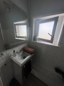 ein weißes Bad mit einem Waschbecken und einem Fenster in der Unterkunft Fenêtre sur mer in Le Portel