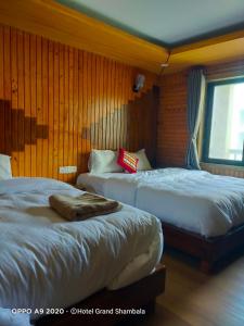 2 Betten in einem Zimmer mit Holzwänden und einem Fenster in der Unterkunft Hotel Grand Shambala in Muktināth