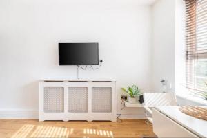 un soggiorno bianco con TV a schermo piatto a parete di Stunning 1 bed flat in the heart of Greenwich a Londra