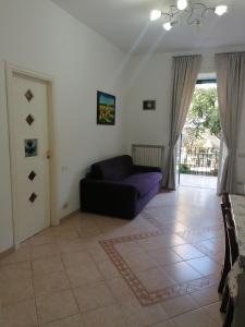 a living room with a purple couch and a door at Casa Anna in Cava deʼ Tirreni