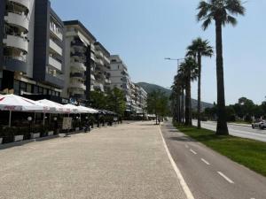 eine Straße mit Sonnenschirmen und Palmen in einer Stadt in der Unterkunft Apartments Vlora Holidays in Vlorë