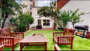 a yard with three benches and a table and a grill at Maison / Porte de Versailles in Vanves