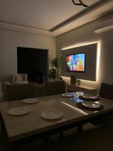 شقة مودرن مقابلة البوليفارد في الرياض: غرفة معيشة مع طاولة وتلفزيون بشاشة مسطحة