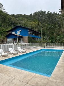 a swimming pool with two chairs and a house at Vila dos pássaros, Quarto 02 in Itapema