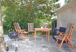 un patio avec trois chaises, une table et un grill dans l'établissement schöne Ferienwohnung mit Kamin und Terrasse in Sassnitz H, à Dwasieden