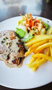 a white plate of food with french fries and meat at H&Q Bangtao Kitchen Studio in Bang Tao Beach
