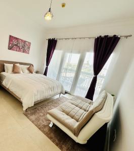 a bedroom with a bed and a chair and a window at Dreams & Themes Ansam Yas Island 108A3 in Abu Dhabi