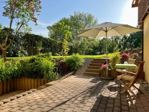 un patio con sombrilla, banco y escaleras en Ferienwohnung mit Gartenblick, en Wilhelmsdorf