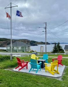 a group of colorful chairs and a table in the grass at Storytellers Retreat in Twillingate