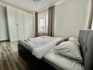 um quarto com uma cama com lençóis brancos e uma janela em YamaLux Apartments - Cozy Double - WestSide 3 em Floresti