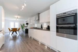 a kitchen with white cabinets and a table with chairs at Stunning 4 Bed 3 Bathroom Home 