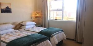 a hotel room with two beds and a window at Secrets 1 at Waterkant 7 in Jeffreys Bay