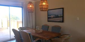 a dining room with a wooden table and chairs at Secrets 1 at Waterkant 7 in Jeffreys Bay