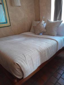 Una cama con sábanas blancas y almohadas. en Woodmere Serviced Apartment, en Nairobi