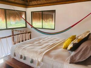 Schlafzimmer mit einem Bett und einer Hängematte an der Wand in der Unterkunft Ca Nikte Cabañas in El Cuyo